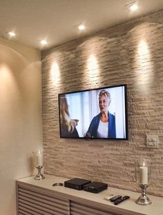 a flat screen tv mounted to the side of a brick wall in a living room