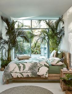 a bedroom with palm trees in the window and plants on the wall behind the bed