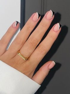 a woman's hand with black and white manies on it, holding a gold ring