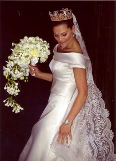 a woman in a wedding dress holding a bouquet of flowers and wearing a tiara