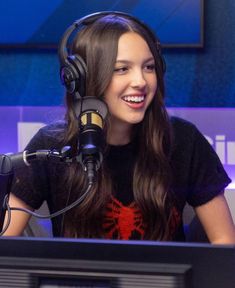 a woman sitting in front of a microphone wearing headphones