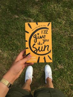 a person holding up a book in their hands with the title i'll give you sun written on it