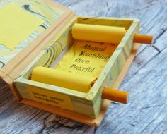 an open book with two pencils in it on a wooden table next to some books