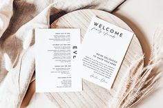 two wedding programs sitting on top of a wooden plate next to a feathery fan