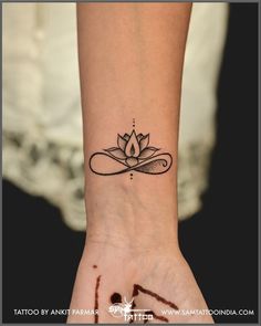 a woman's wrist tattoo with a lotus on the middle of her left hand