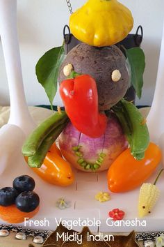 a vegetable figurine sitting on top of a plate with peppers, carrots and other vegetables