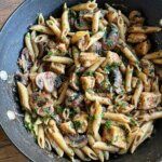 a pan filled with pasta and mushrooms on top of a wooden table