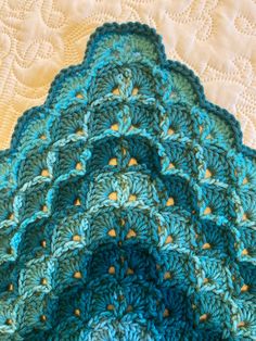 a blue crocheted blanket on top of a bed