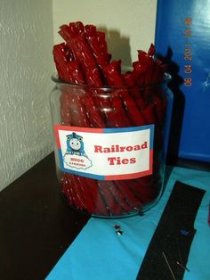 a jar filled with red candy sticks on top of a table