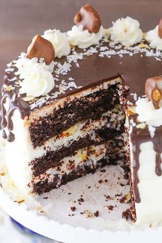 there is a chocolate cake with white frosting and nuts on the top it has one slice cut out