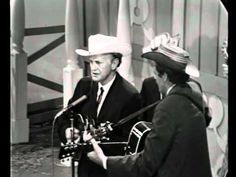 two men in suits and hats are talking to each other while one man is holding a microphone