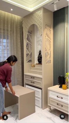 a woman standing next to a white dresser in a room with two drawers and a mirror on the wall