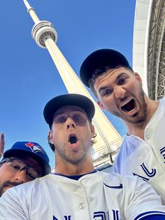 two baseball players standing next to each other in front of a tall building with a sky background