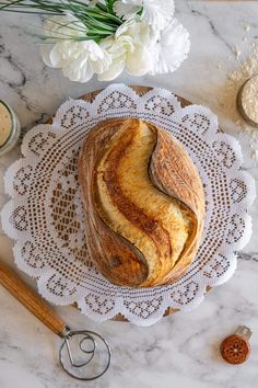 a loaf of bread sitting on top of a white doily next to some flowers