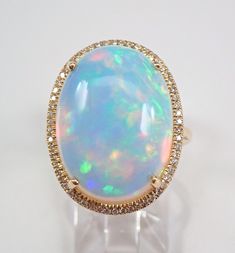 14K Yellow Gold Diamond and Opal Engagement Ring. This ring is set with one genuine Oval Opal in the center and fifty-eight genuine round brilliant diamonds. This Opal measures 20 X 15 mm and weighs 11.27 carats. The diamonds in this ring are G color, SI in clarity and weigh a total of .21 carat. This ring is Solid 14KT Yellow Gold, weighs 7.2 grams and is a finger size 7, which can be resized free of charge (please inquire about sizing with the finger size you need). This ring will be accompani Yellow Gold Opal Ring, 7 October, Gold Opal Ring, Engagement Ring Size, Opal Ring Gold, Opal Engagement, Halo Setting, Engagement Rings Opal, Engagement Ring Sizes