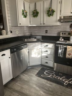 a kitchen with white cabinets and black counter tops is decorated for the holiday season by wreaths