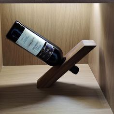 a bottle of wine sitting on top of a wooden shelf next to a corkscrew