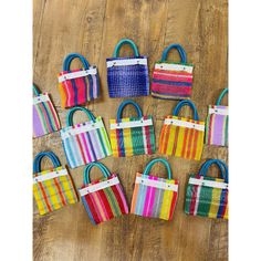 colorful handbags are laid out on a wooden floor with tags attached to the handles