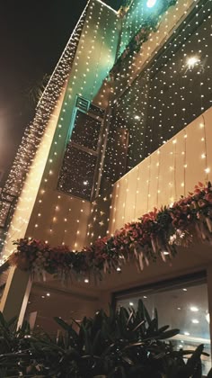 the building has lights all over it and is decorated with greenery on both sides