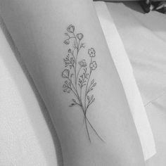 a black and white photo of a flower tattoo on the left arm, with small flowers growing out of it