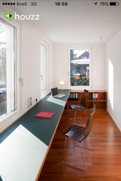 an empty room with two chairs and a desk in front of a window that has a laptop on it