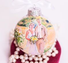 a wedding ornament with a bride and groom on it sitting next to pearls