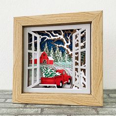 a red truck driving down a road next to a snow covered tree filled forest in front of a wooden frame