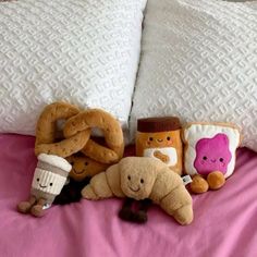 several stuffed animals on a bed with pillows