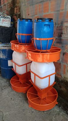 three blue and one white buckets are stacked on top of each other in front of a brick wall