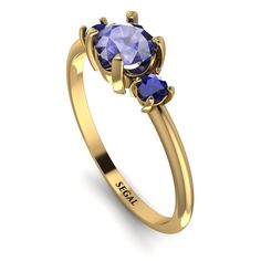 a yellow gold ring with two blue sapphire stones on the side and an inscription that reads,