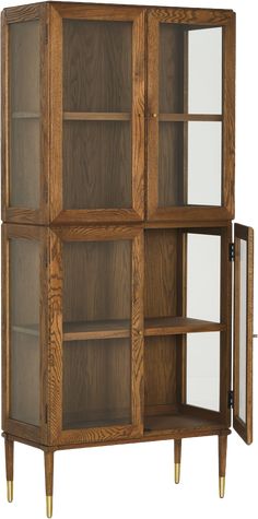 an oak bookcase with glass doors and brass legs on the bottom, in front of a white background