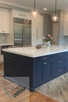 a large kitchen with an island in the middle and two pendant lights hanging from the ceiling