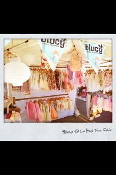 an outdoor market with lots of clothes hanging from it's walls and lights on the ceiling