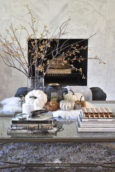 a coffee table topped with books and a vase filled with flowers next to a fire place