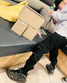 a young man sitting on top of a bench next to a box