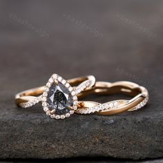 two yellow gold wedding rings with diamonds on the top and bottom, sitting on a rock