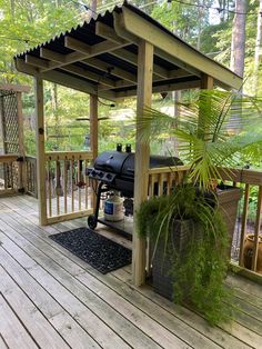 a wooden deck with a grill and potted plants on it's end area