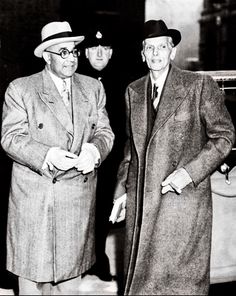 two men in suits and hats standing next to each other