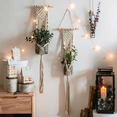 three macrame plant holders hanging on the wall with string lights and potted plants