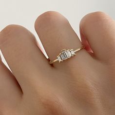 a woman's hand wearing a gold ring with three baguettes