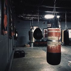 an empty gym with boxing gloves hanging from the ceiling and punching bags on the wall