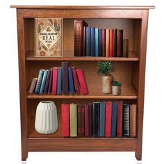 a wooden book shelf filled with books next to a potted plant on top of a table