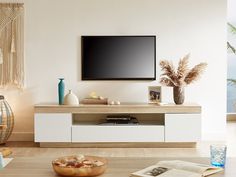 a flat screen tv sitting on top of a white entertainment center next to a vase