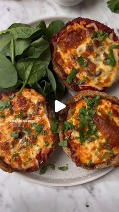 three mini pizzas on a plate with spinach leaves