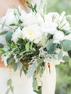 a bridal holding a bouquet of white flowers and greenery