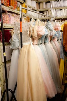 there are many dresses hanging on the rack in this store, all different colors and sizes