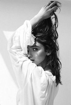 a black and white photo of a woman with her hair blowing in the wind,