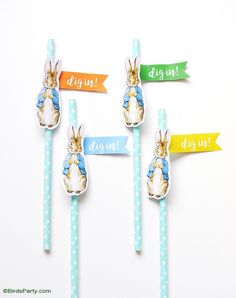 three easter bunnies on top of blue and white straws with colorful paper banners