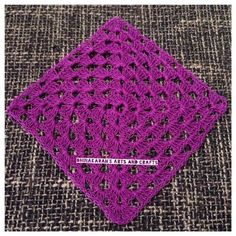 a purple crocheted square sitting on top of a carpet