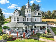 a large white house with a steeple on the top floor and a porch in front of it